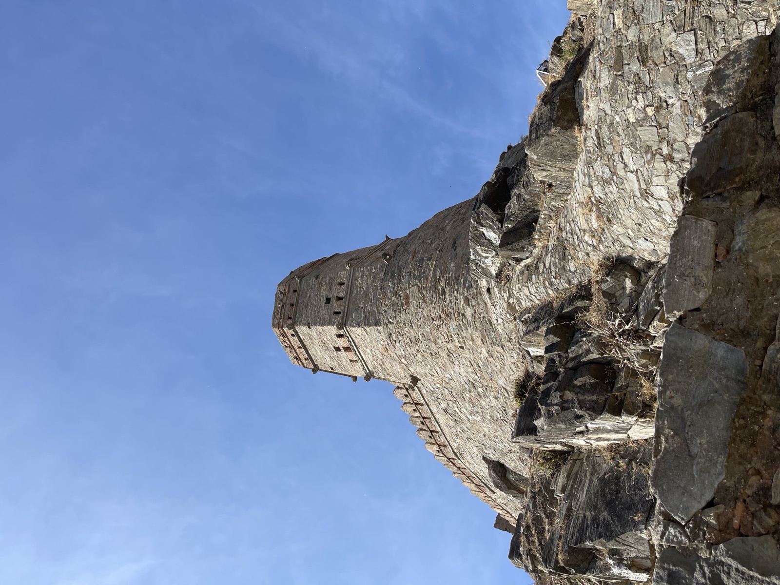 Stone fort watchtower rising from rocky ramparts against a bright blue sky
